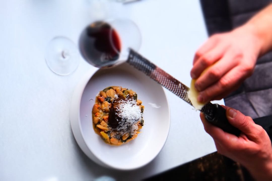 Kaas wordt over een gerecht met bonen geraspt